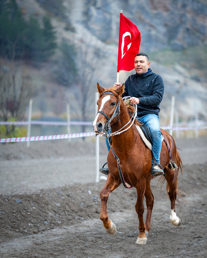 A man rides a horse holding a Turkish flag in Adıyaman, showcasing a blend of tradition and national pride.