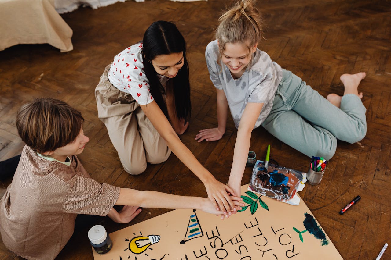 Three teenagers work together on an artistic project indoors, enhancing creativity and teamwork.